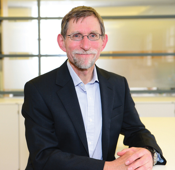 An image showing Tim Oates CBE sat a desk smiling at the camera